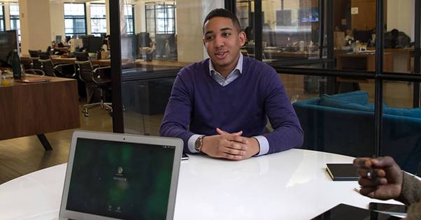 man sat his desk smiling 